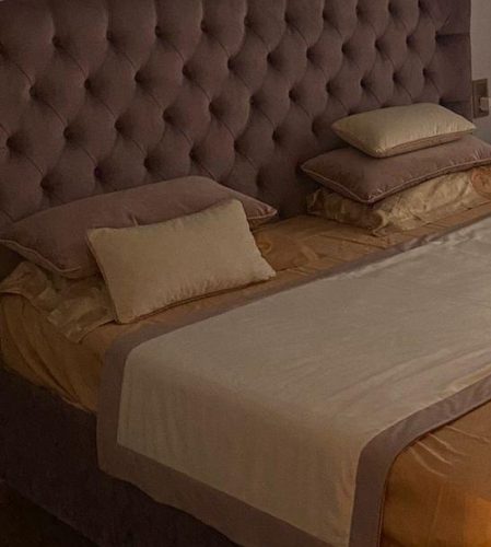 Декоративные подушки и покрывало саше с окантовкой на кровати в номере гостиницы крупным планом - 1.