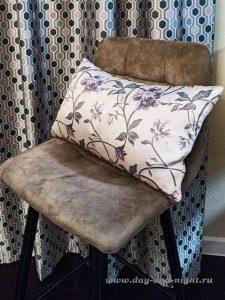 Декоративная подушка с узором на стуле и фрагмент шторы крупным планом.